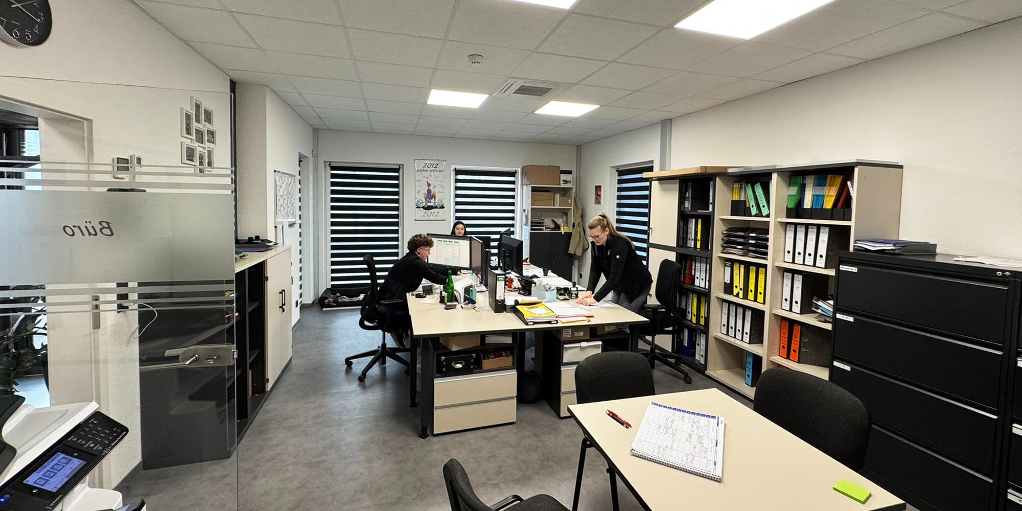 Büroarbeitsplatz mit Mitarbeitenden bei administrativen Tätigkeiten im Orthopädiebetrieb.